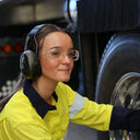 Woman wearing clear Syren safety glasses and ear protection beside a truck