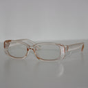 Clear Syren safety glasses with side shields, viewed from the side on a light grey surface